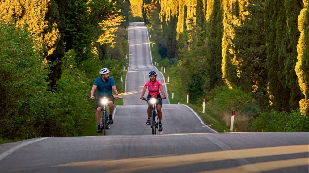 Toerfietsers met verlichting op heuvelachtige weg